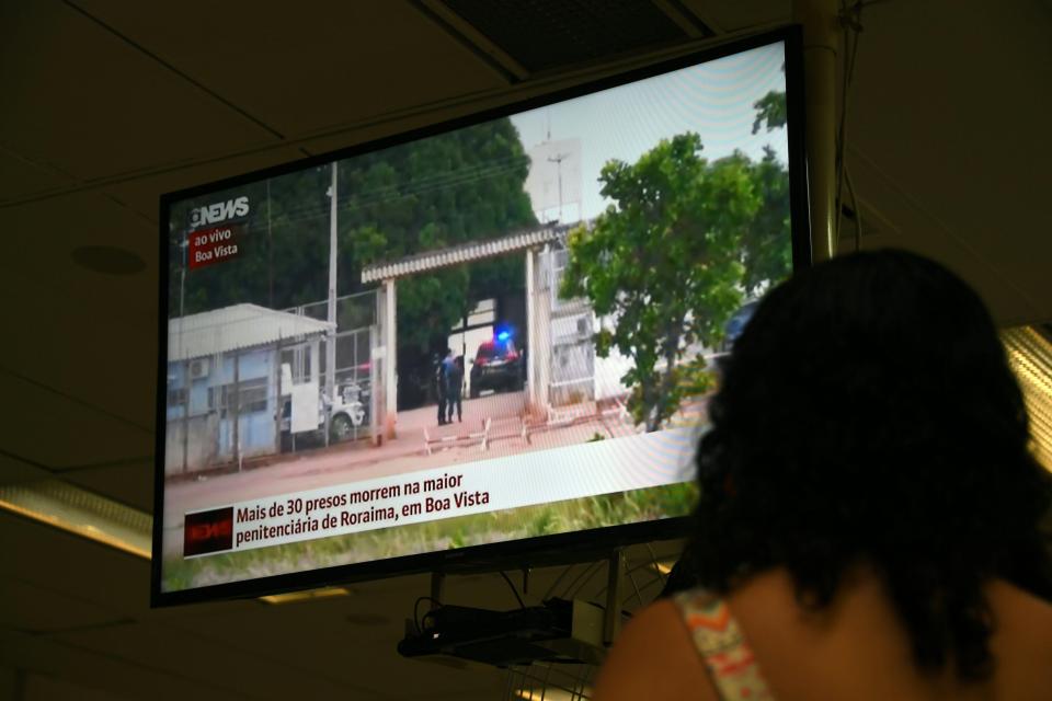  A woman watches on television news about the riot