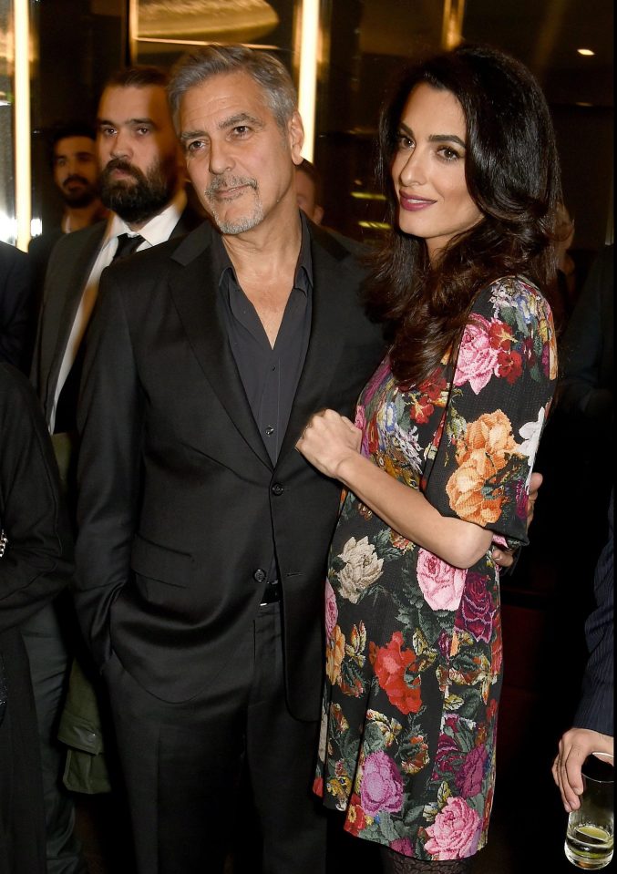  Amal, wearing a loose-fitting flowery dress, poses for the cameras with her hubby