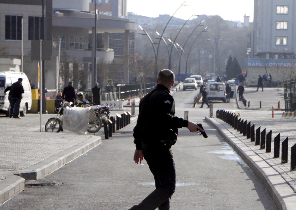  An officer armed with a pistol patrols the scene of the shooting