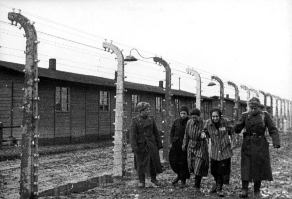  This black and white photo shows Soviet soldiers walking with the prisoners they freed in Auschwitz