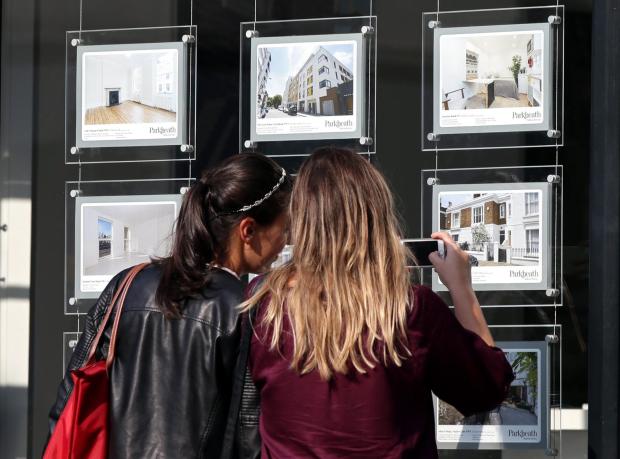 Two girls looking at an estate agent's window