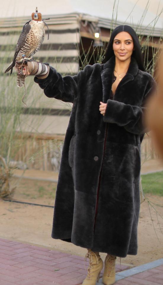  Kim Kardashian posed with a falcon while wearing a black faux coat in Dubai today