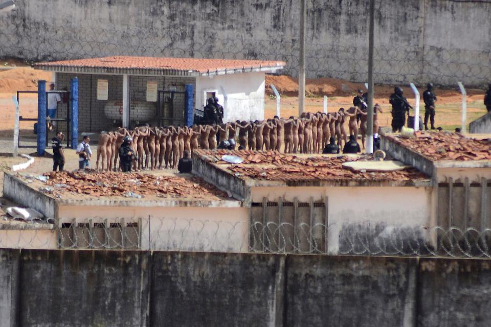 Naked inmates stand in line while surrounded by police after a riot at the Alcacuz prison in Nisia Floresta, Rio Grande do Norte state, Brazil