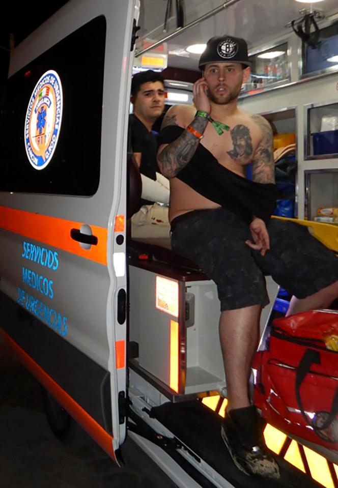  An injured man wearing a sling uses his mobile phone while being treated in an ambulance