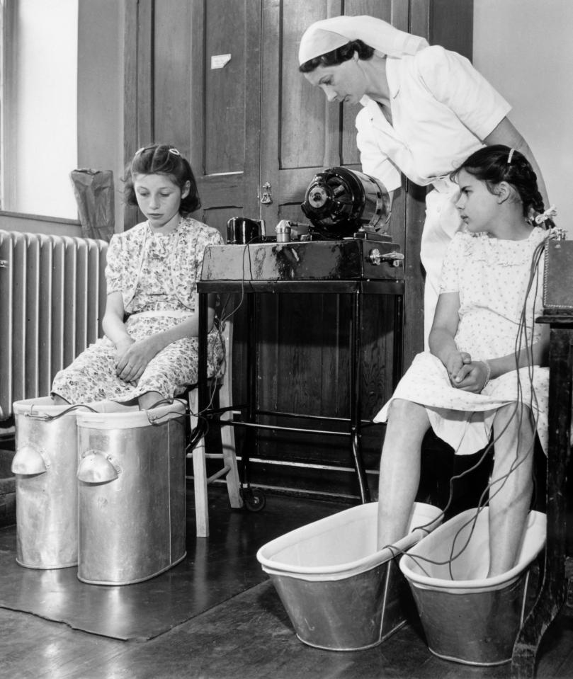  Two girls at a Bristol health centre's orthopaedic department being treated by a nurse. The girl on the right is having a faradiac current bath for flat feet and the other girl has a sinusoidal footbath - also for flat feet