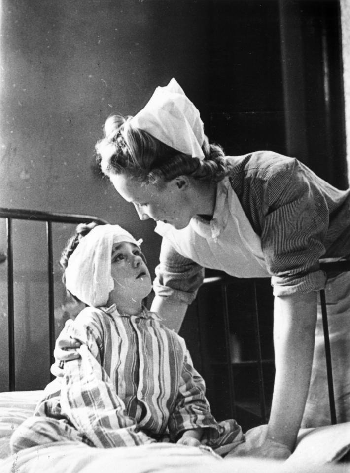 Miners and steelworkers in Tredegar pay the Workmen's Medical Aid Society twopence out of every pound they earn to go towards their medical, dental and optical services. A nurse bending over a small boy to see to his injuries