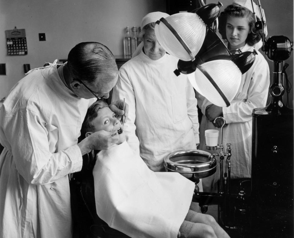 A dentist at a Bristol health centre surgery tends to a young boy with his assistants