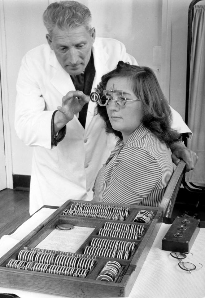 An optician working at a Bristol clinic with a young woman having a eye test. Glasses were free under the NHS on a doctor's prescription. But "fancy frames" were charged for 