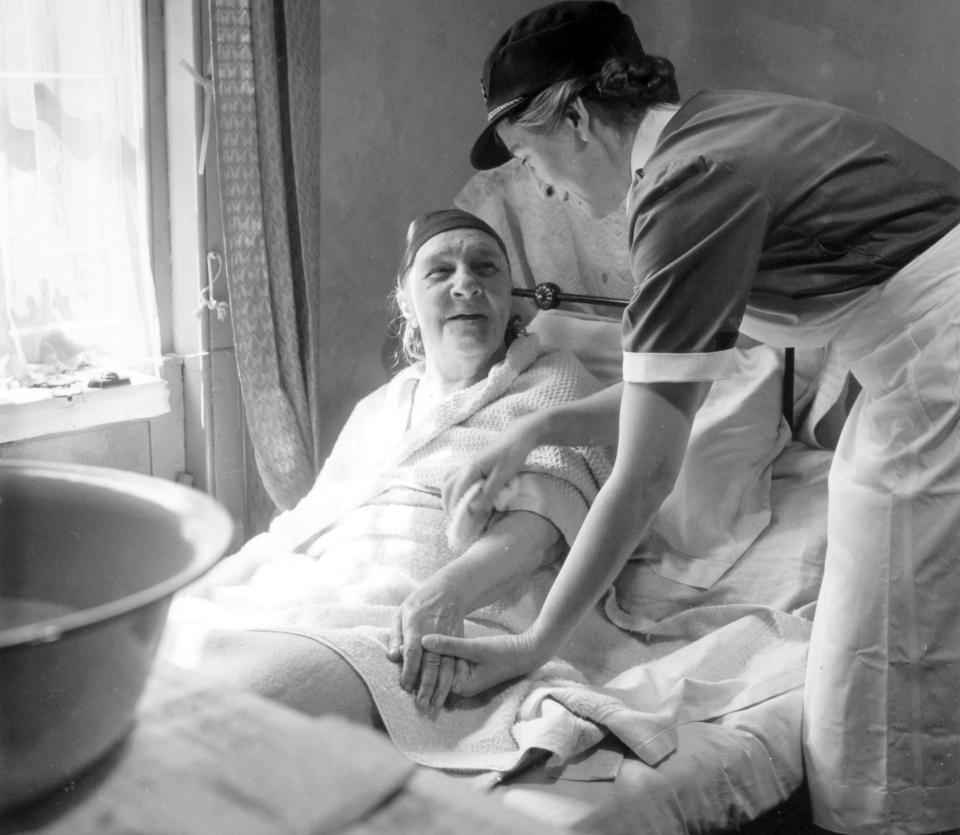 An elderly woman being tended to at home by a nurse, a service offered free of charge on the NHS