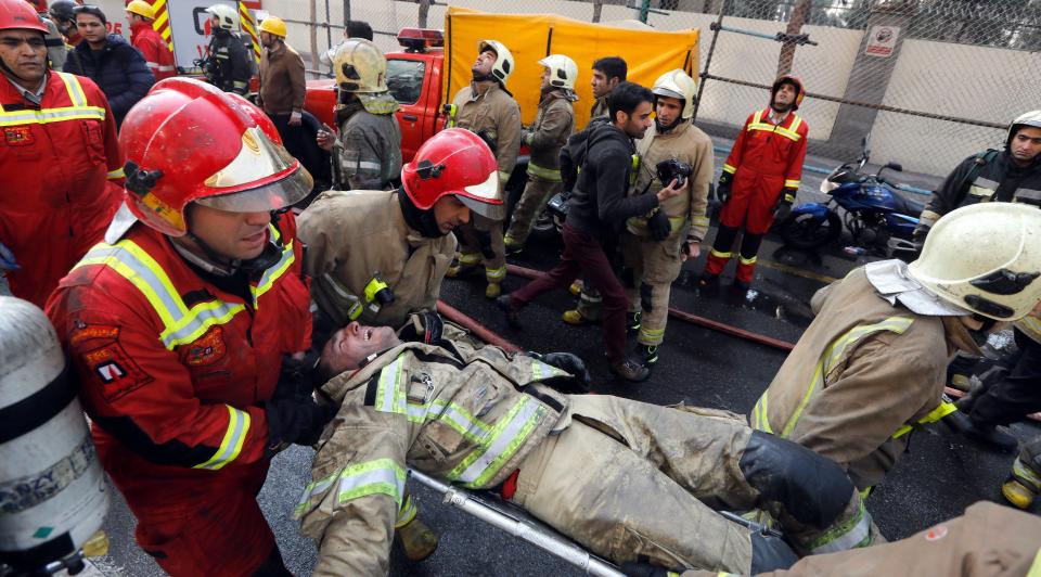  Iranian fire fighters carry one of their injured colleagues out of the wreckage