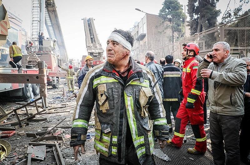  A wounded firefighter stands at the site of a collapsed high-rise building in Tehran