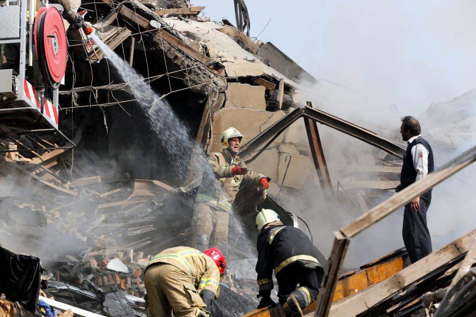  Iranian fire fighters try to control a fire as it rises from