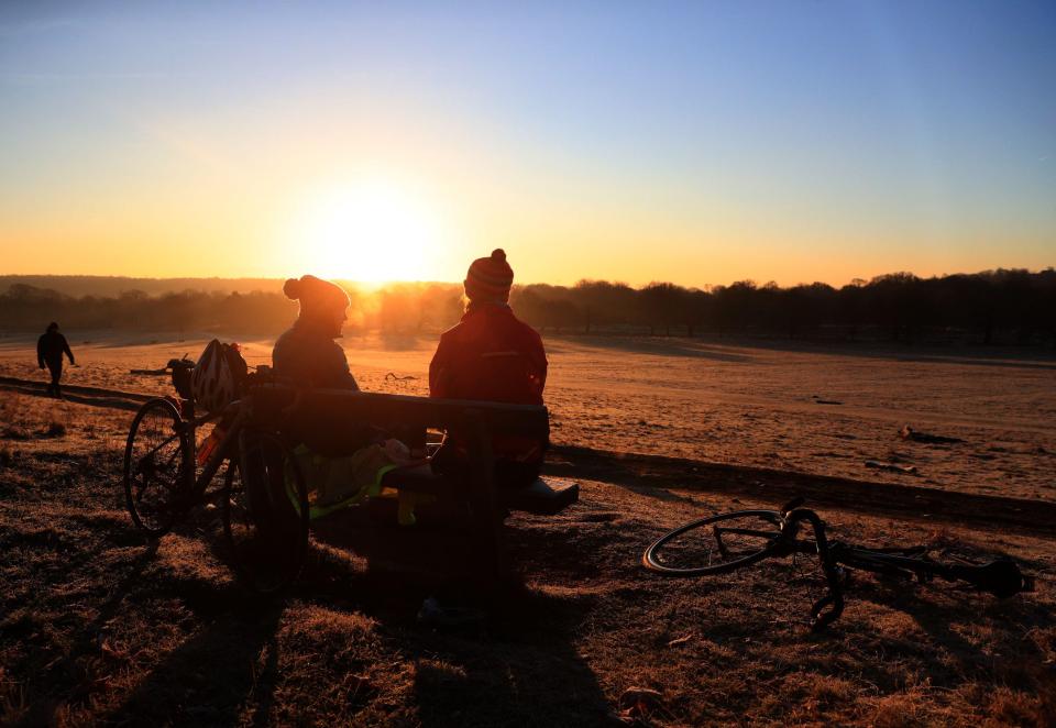  Two cyclists made the most of the chilly weather by watching a beautiful sunrise in Richmond Park, London,