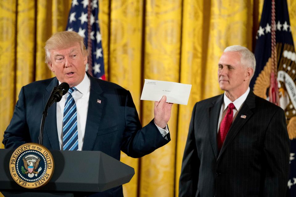 Trump holds up a letter left for him by former president Barack Obama during the swearing in ceremony