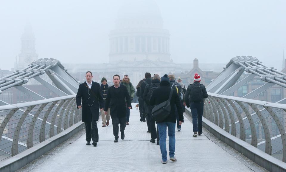  People walk across Millennium Bridge in London towards St Paul's Cathedral shrouded in fog