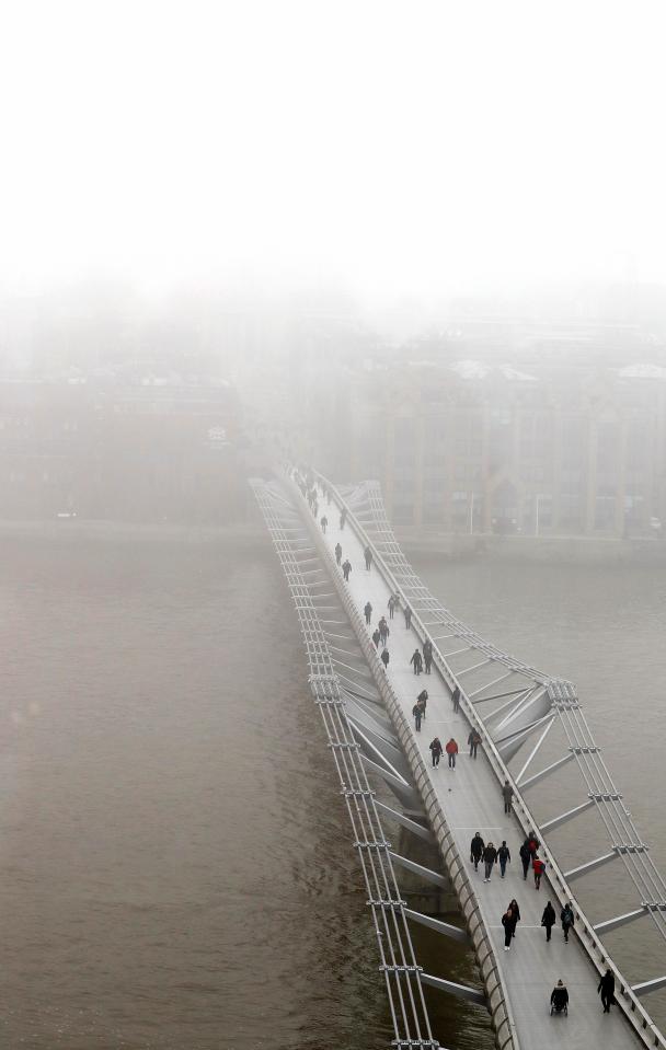  Pedestrians walk over the Millennium Bridge as fog shrouds St Paul's Cathedral in London