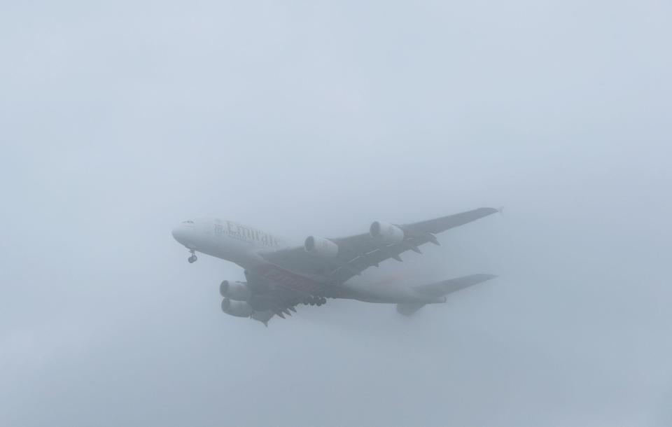  An Emirates A380 plane comes into land through the fog at Heathrow Airport - the airport was forced to cancel more than 100 flights