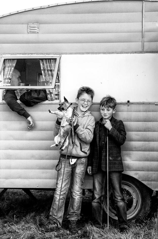  Two lads play with the family dog outside their caravan