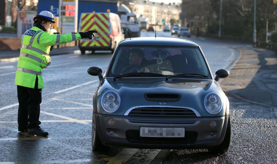  An officer pulls a motorist over as cops launch crackdown on drivers checking social media behind the wheel