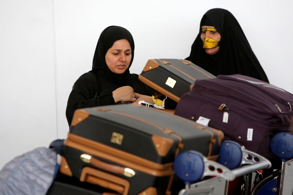 Women check their luggage after arriving on a flight to New York from Dubai