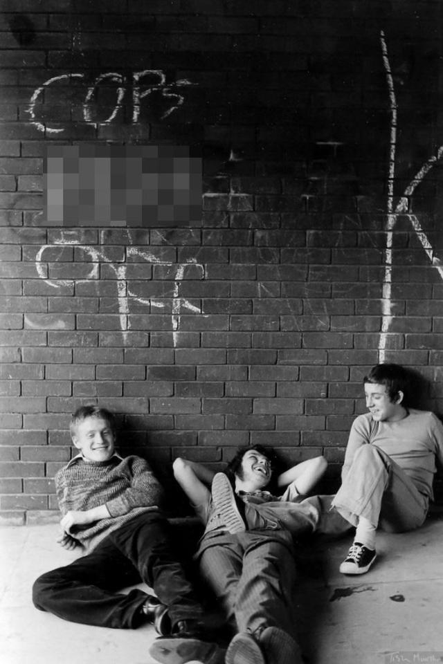  Laughing boys pose next to a message on the wall condemning the police