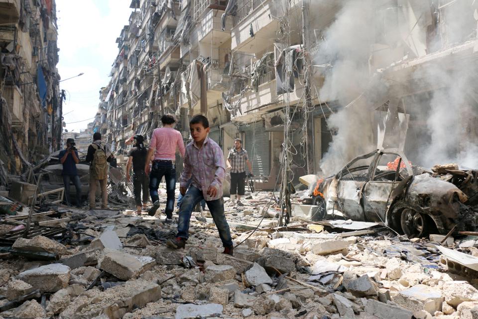  People walk amid the rubble of destroyed buildings following a reported air strike on the rebel-held neighbourhood of al-Kalasa in the northern Syrian city of Aleppo