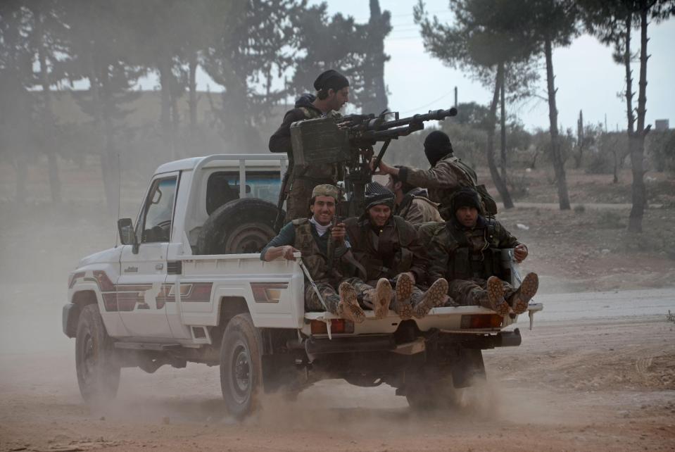  Opposition fighters sit in the back of an armed pick-up truck as they drive in the village of Bizaah, north of Aleppo