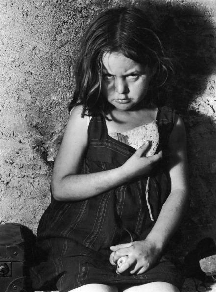  1939: A young refugee from Madrid clutches a piece of bread in the aftermath of the Spanish Civil War bombings