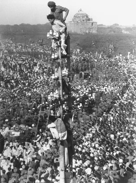  1948: Crowds watching Mohandas K. Gandhi's funeral, as some spectators climb narrow tower to get better view