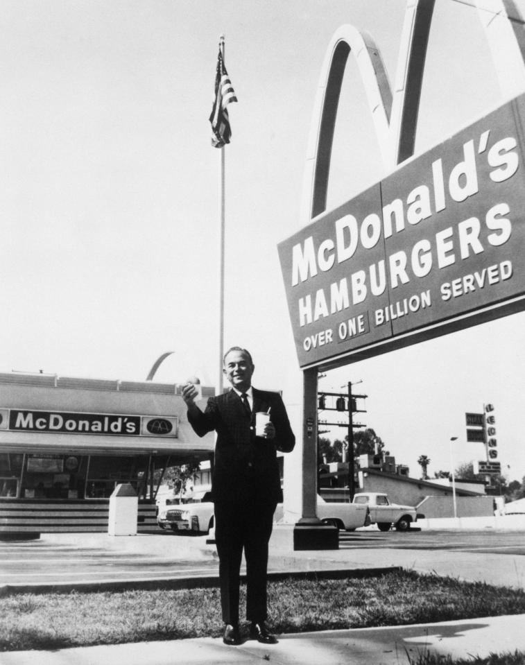  Founder and chairman of McDonald's Corporation, Ray Kroc, stands outside one of his franchises, holding a hamburger and a drink