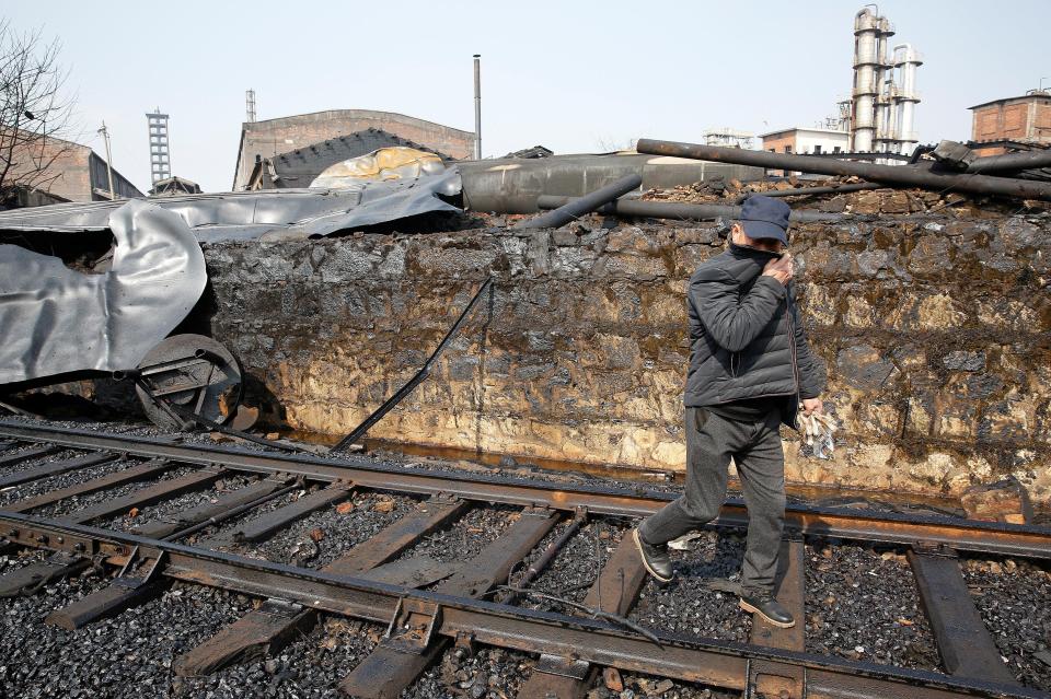  A man covers his nose as he walks near the site of an explosion