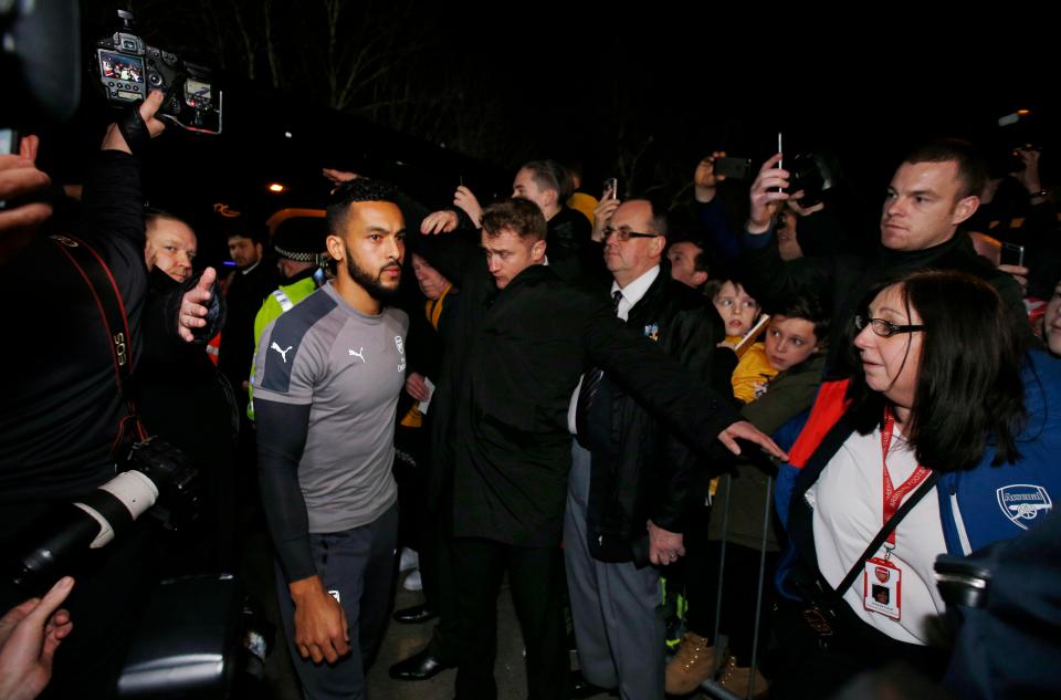 Theo Walcott next to a minder as he makes his way into the stadium