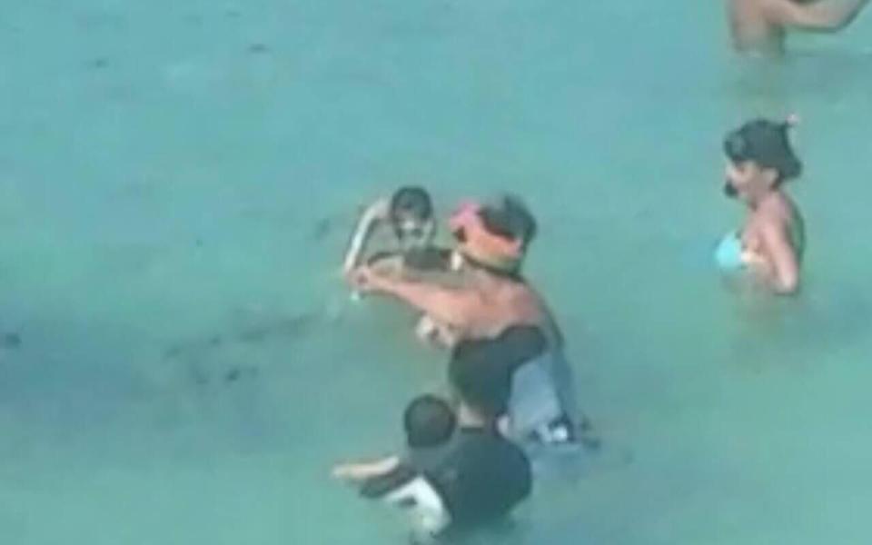 Olga Smirnova, in the pink visor, was arrested for feeding bread to fish near an ecologically-sensitive coral reef