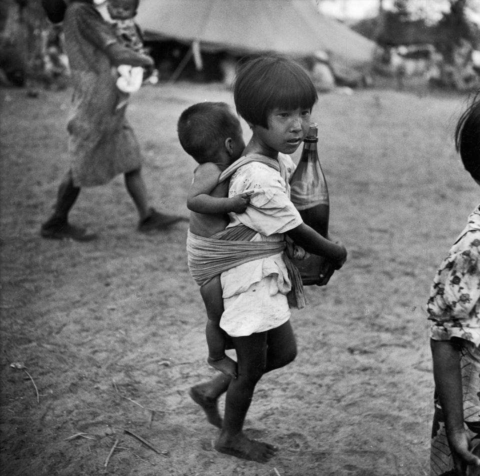  Young Japanese girl carries a bottle of water and a baby on her back as she makes her way through a village on Saipan