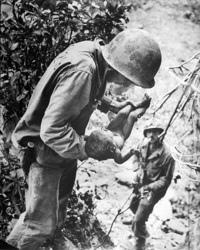  1944: US marine cradles a near-dead infant after finding the baby face down in the dirt while clearing out Japanese caves in Saipan