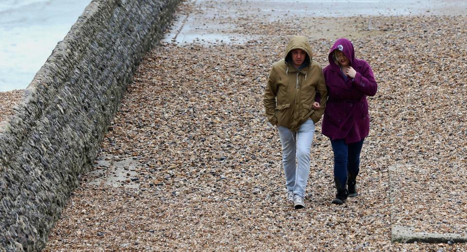  Couple keep their hoods up as the walk along the sea wall in Brighton