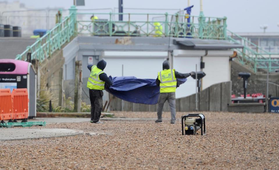  Workmen struggle with a tarpaulin in strong winds on Brighton seafront this morning as Storm Doris heads towards Britain