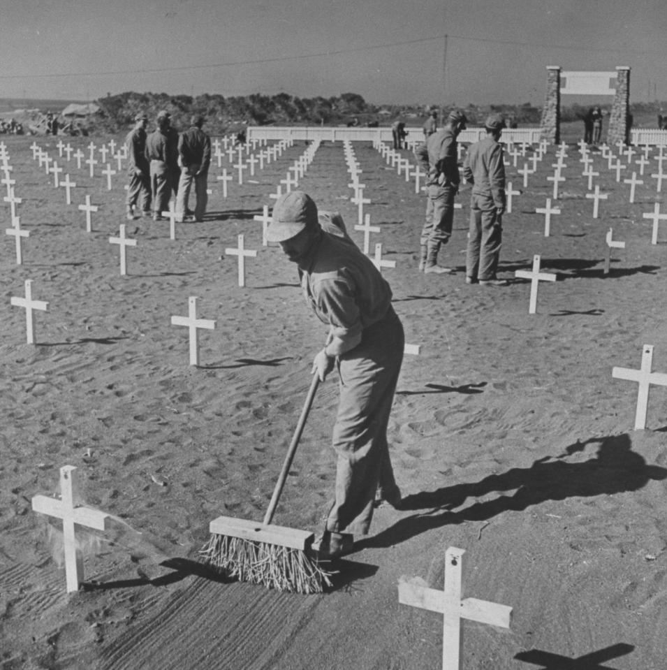  Workers sweep graves at an American military cemetery for those killed during the fight for Iwo Jima