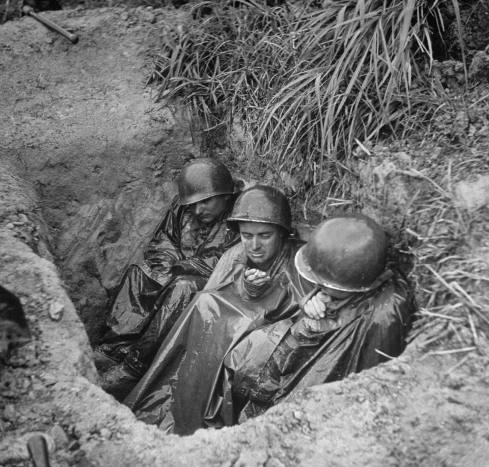  Infantryman Terry Moore, centre, and his fellow soldiers huddle in foxhole during intense sniper fire as they wait to advance on enemy positions