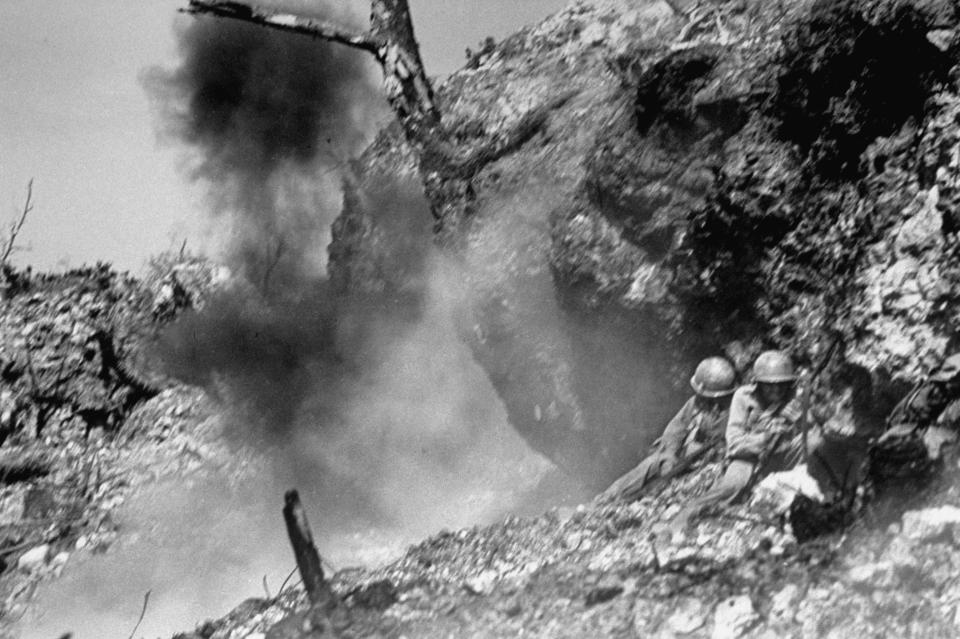  Two soldiers crouch down on a narrow ledge as an enemy mortar shell explodes nearby