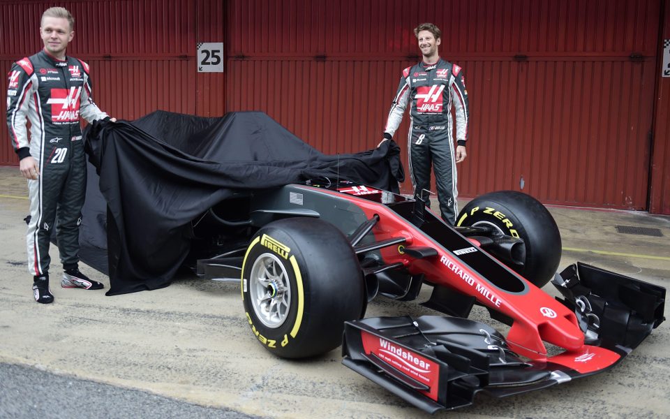 Kevin Magnussen (L) and HAAS F1 Team's French driver Romain Grosjean unveil their new VF17 car