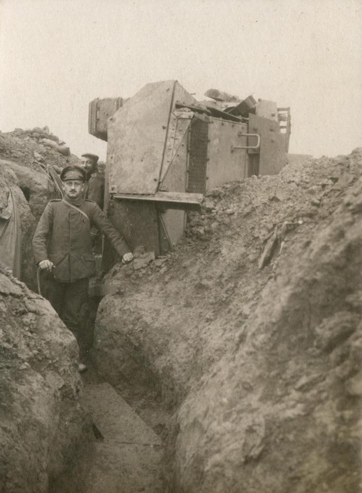  Soldiers pose proudly as a Schneider assault tank lies on its side on the lip of a trench