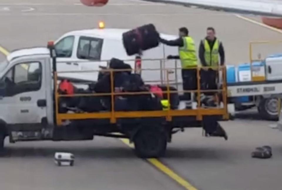  Baggage handlers carelessly flip luggage into a truck at Luton airport