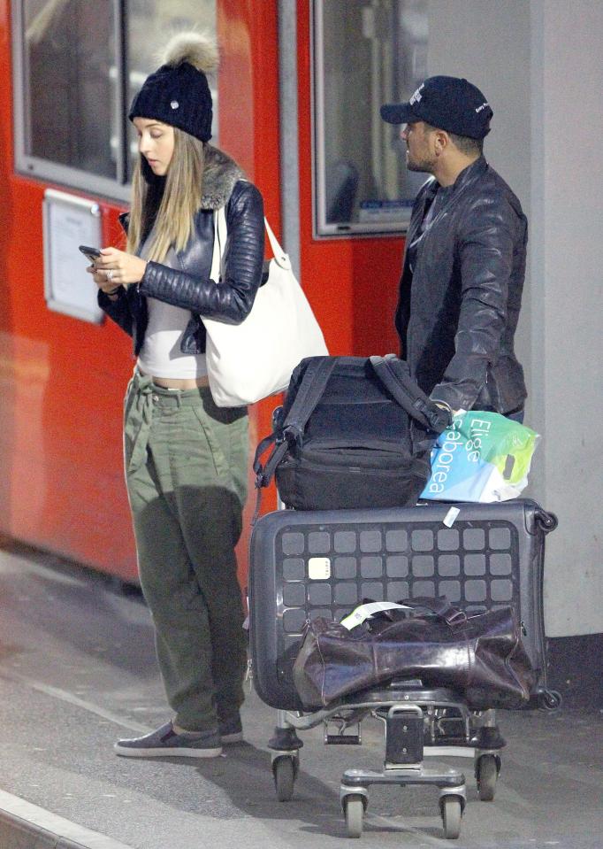 She was seen checking her phone as they waited outside the terminal with their bags