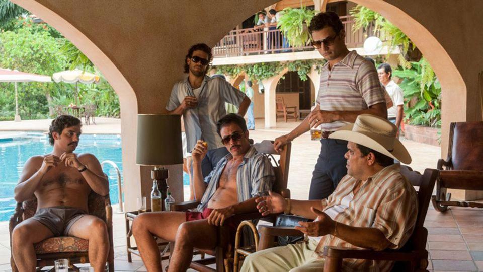  Juan Riedinger stands at the back leaning on the wall in Narcos