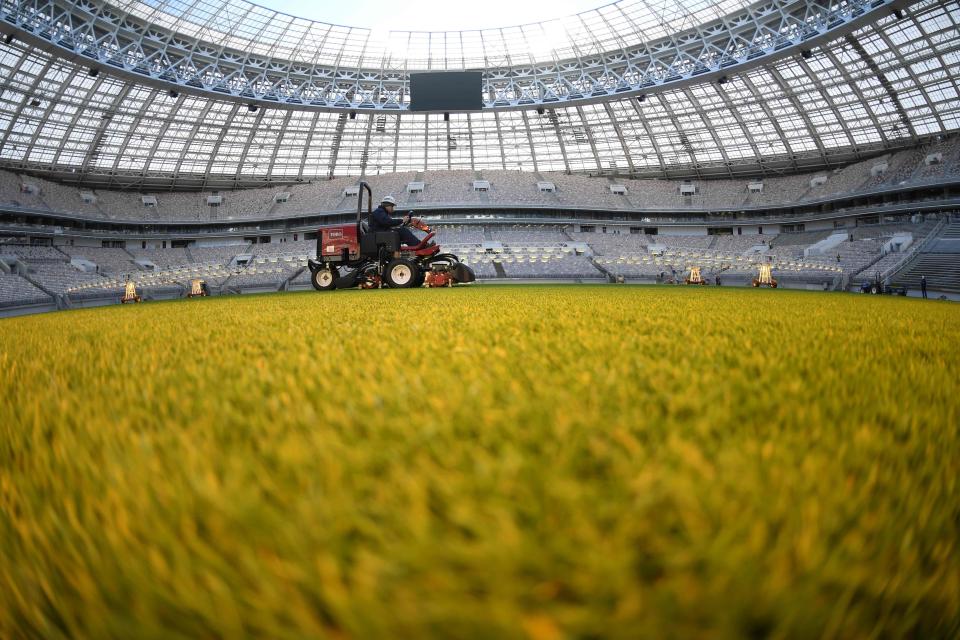 An employee mows the grass on the pitch at the Luznhiki Stadium as work is done to the ground