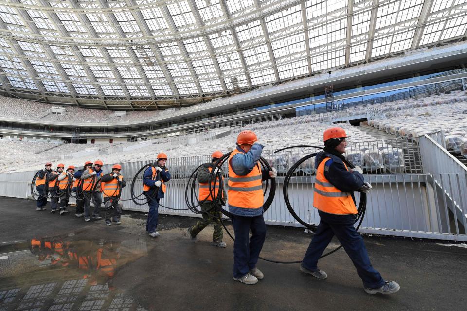 Workmen carry electrical cables past a stand in order to have the stadium fully functioning in time for the World Cup