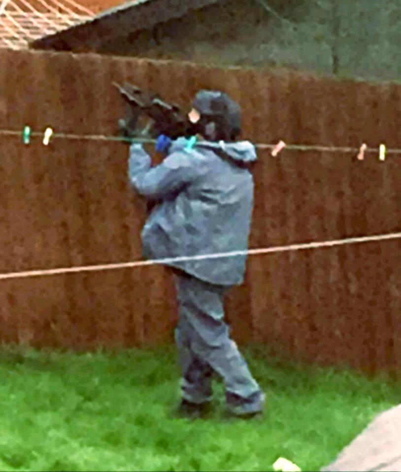  An armed officer trains an assault rifle on the upstairs window on a property in Birmingham