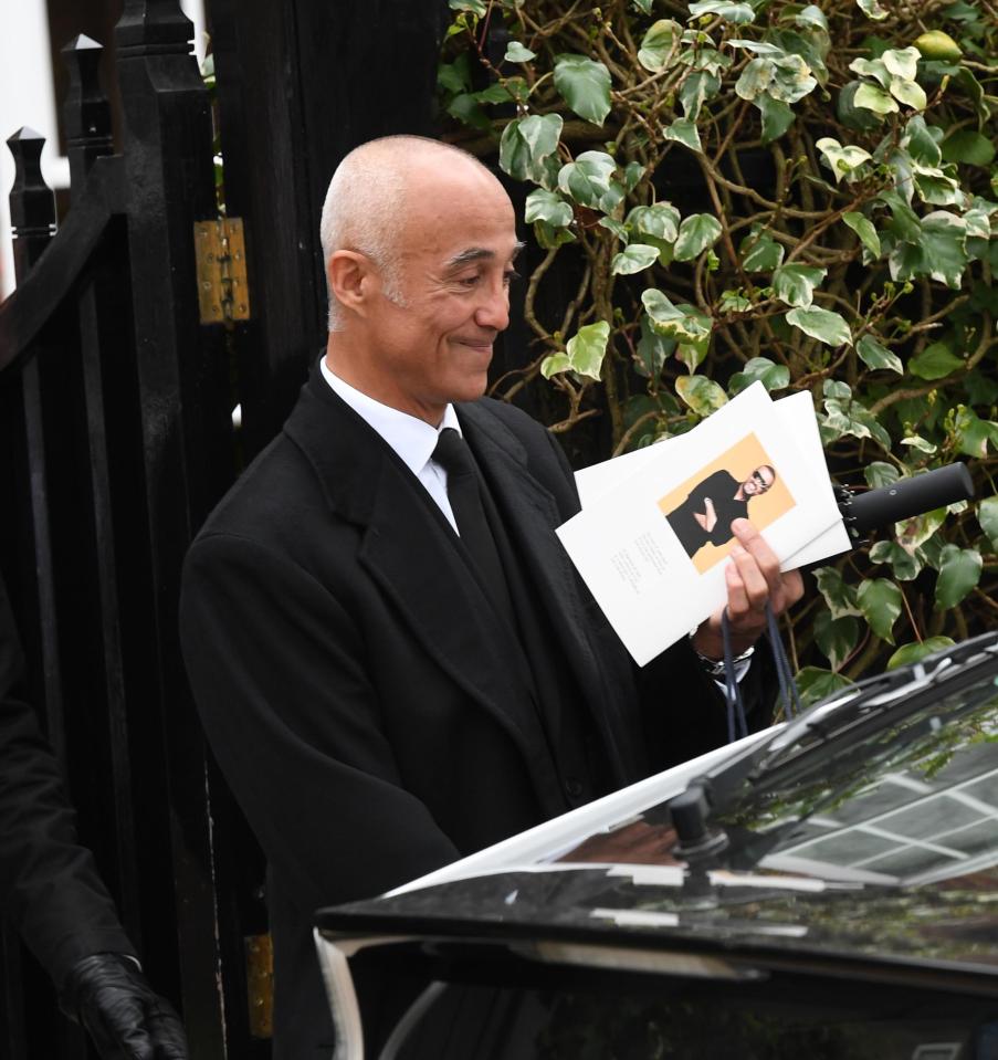  Andrew Ridgeley gives a sad smile as he leaves the service holding his order of service