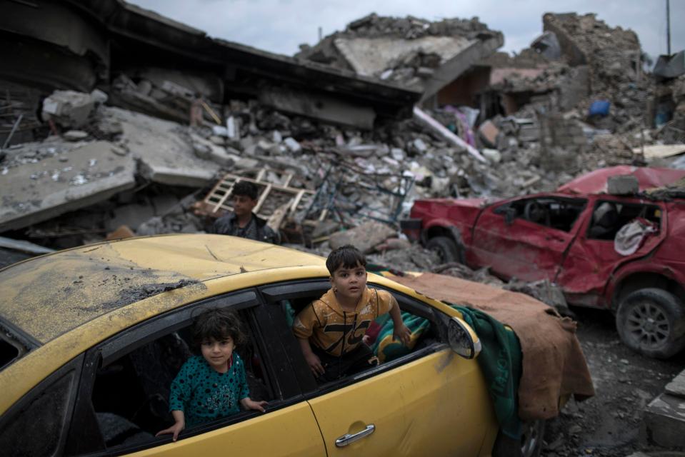  Children play in a car in Mosul, Iraq, which has been devastated by fighting